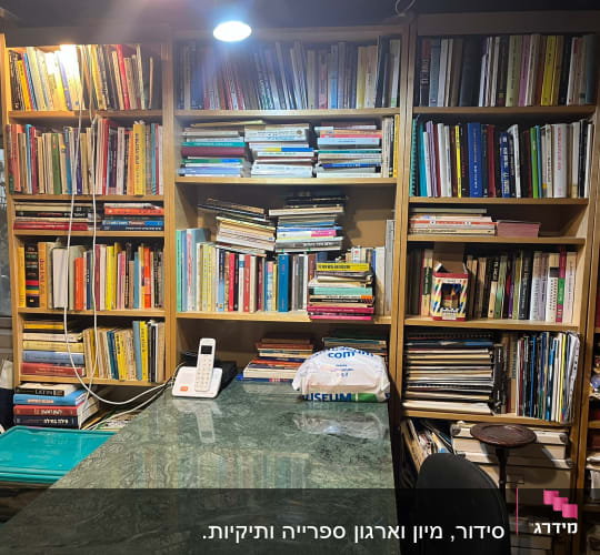 מדפי ספרים מלאים בספרים, טלפון שולחני על שולחן
